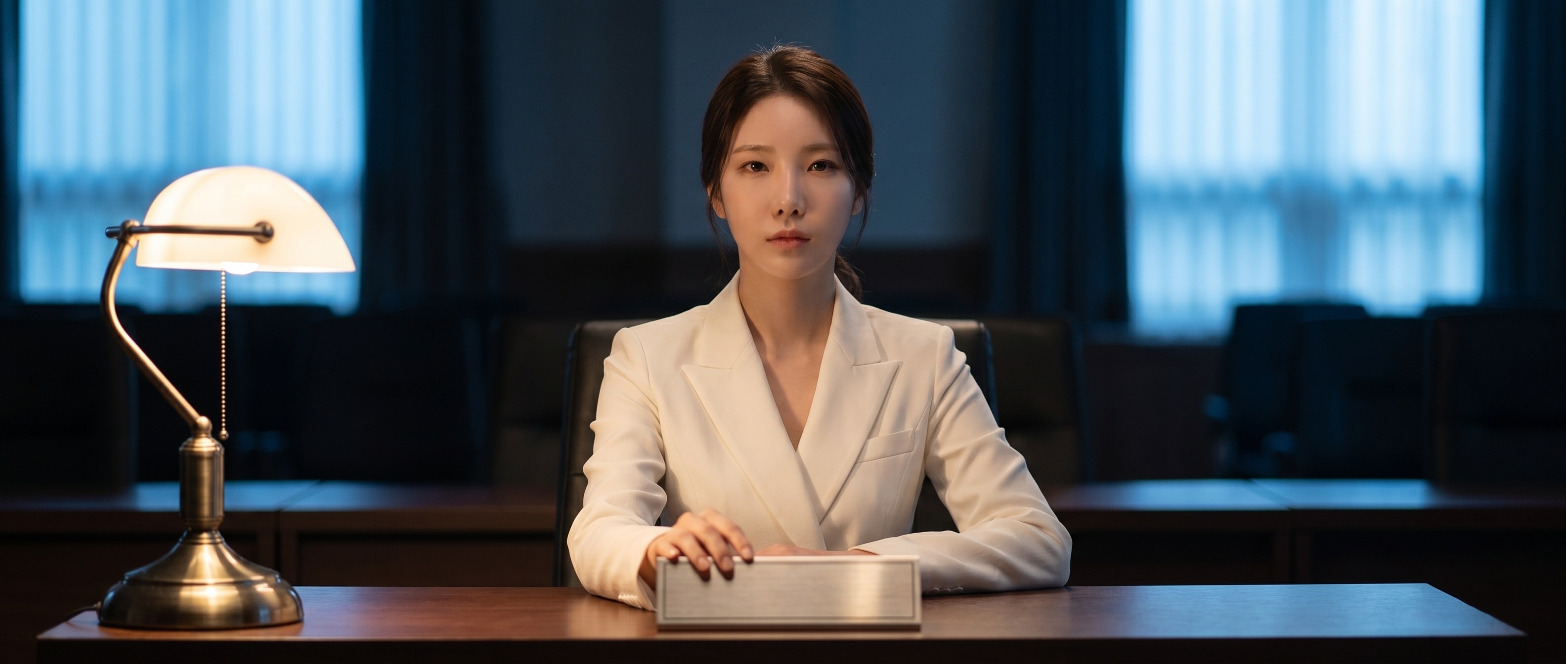 빈 명패에 손을 얹고 정면을 응시하는 루나